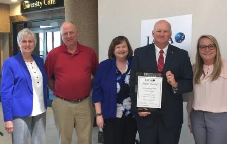 Secretary Hammond poses with office staff holding the IACA award